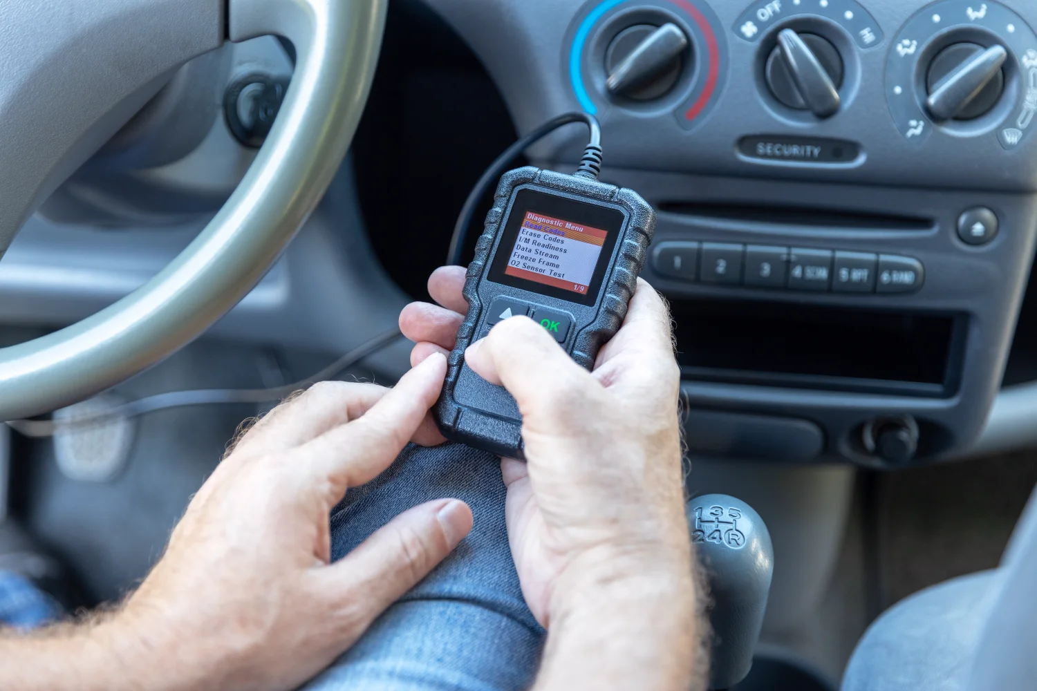 Mechanic using an OBD diagnostic scan tool inside a vehicle