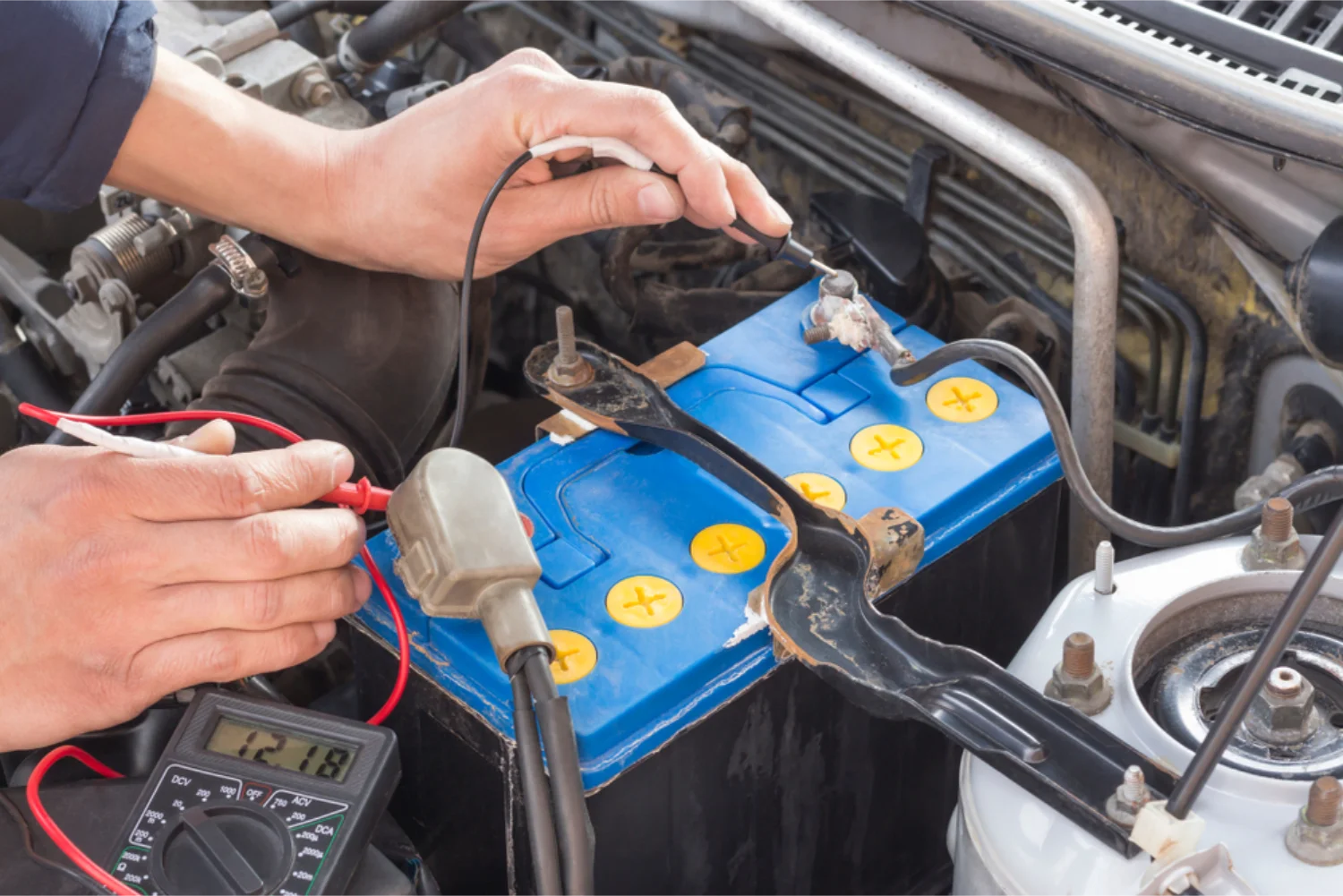 Mechanic testing a car battery with a multimeter
