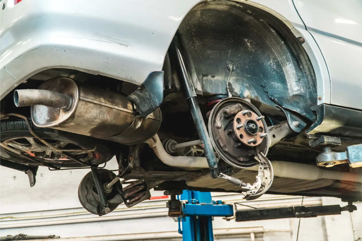 Vehicle underside showing brake and suspension components on a hoist