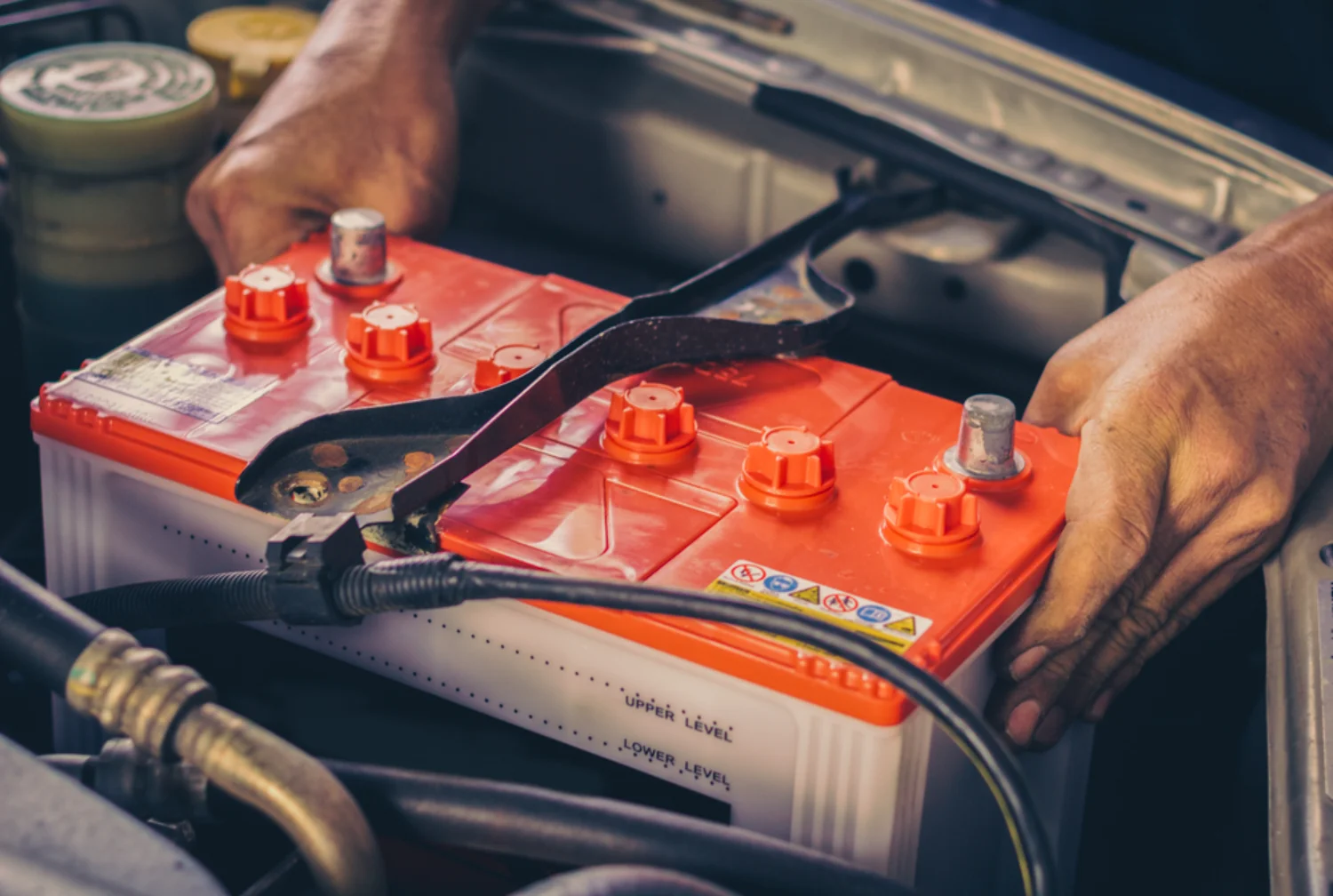 Mechanic replacing a car battery in an engine bay