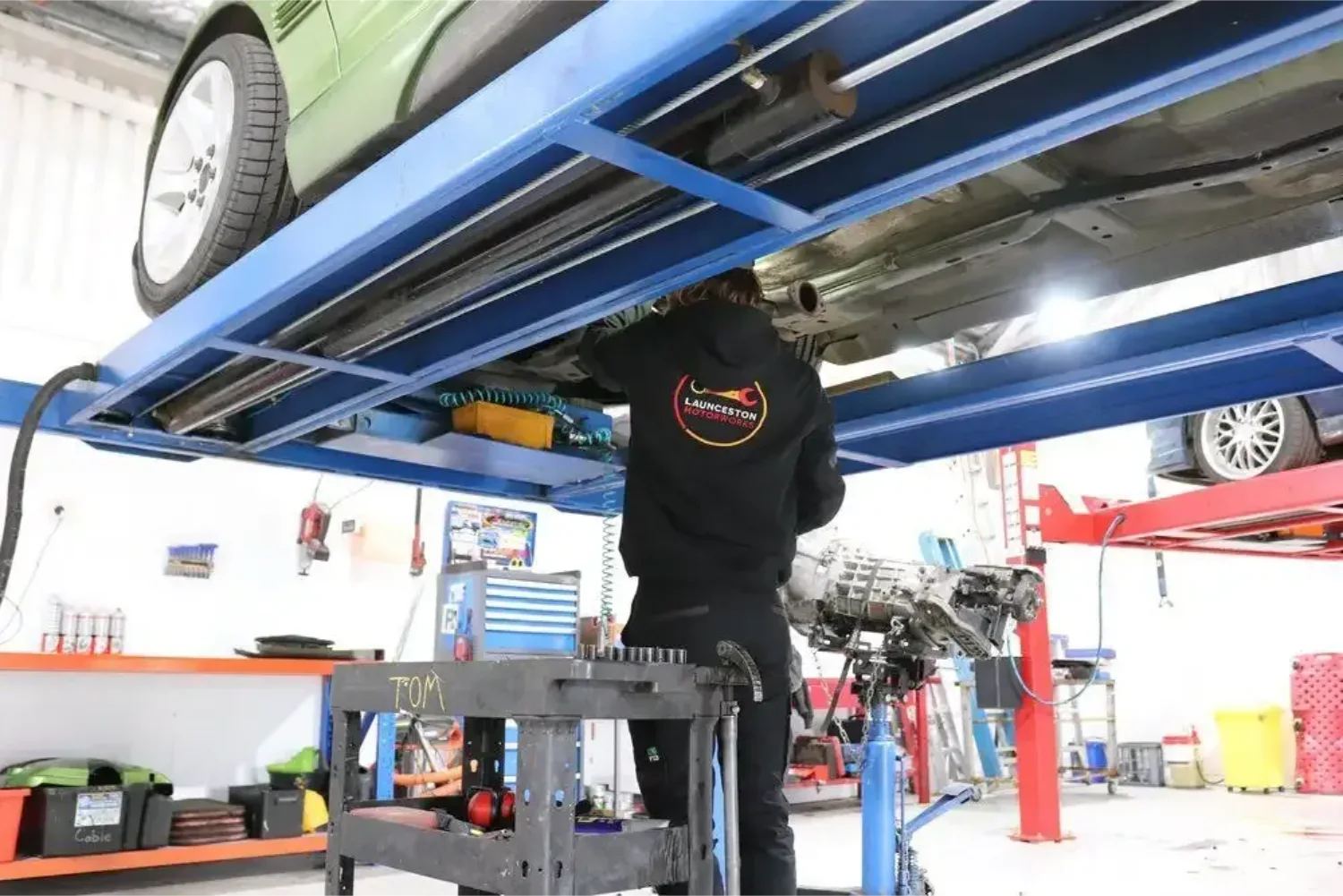 Launceston Motorworks mechanic working under a vehicle on a hoist